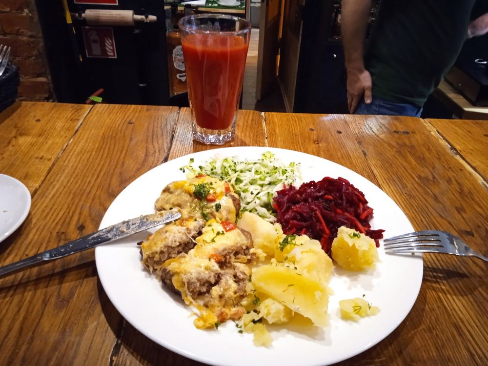 Užkepta mėsa su bulvėmis ir salotomis, šalia pomidorų sultys